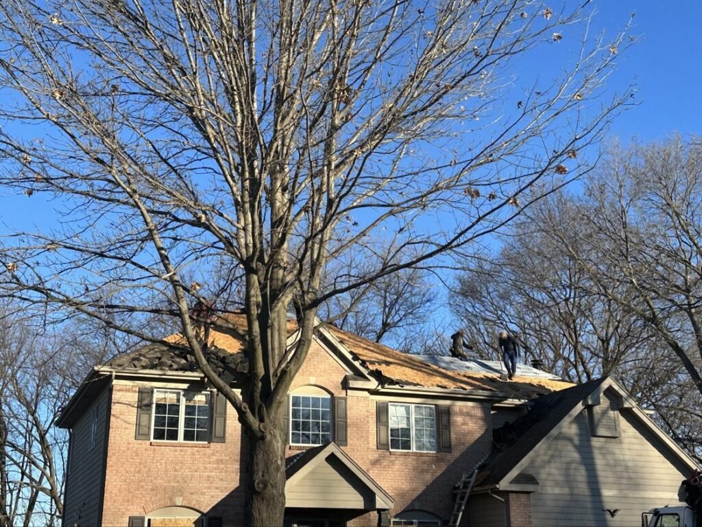 Hutch Unlimited Roofing crew tearing off a brick home roof, Iowa