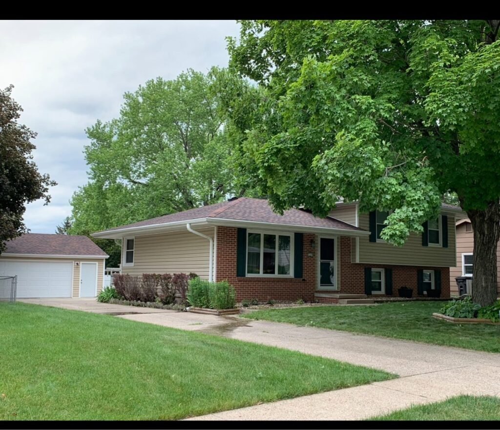 New brown shingle roof on a split-level home with detached garage by Hutch Unlimited Roofing, Iowa