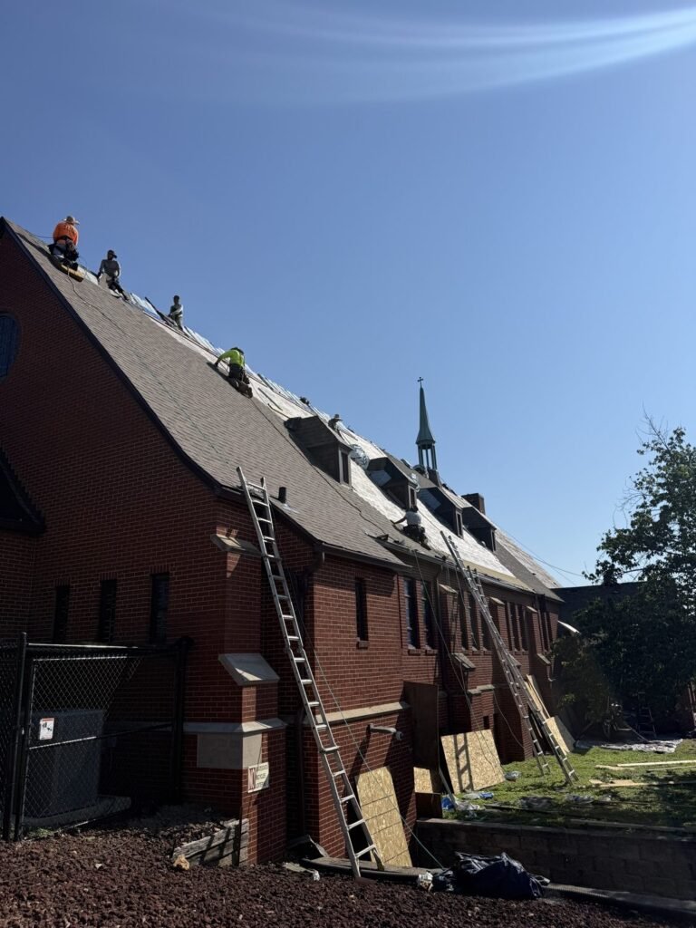 Hutch Unlimited Roofing crew installing shingles on a steep church roof, Iowa