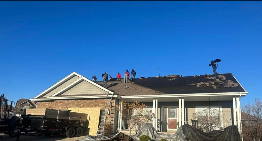 Hutch Unlimited Roofing crew tearing off a ranch home roof with dump trailer on site, Iowa