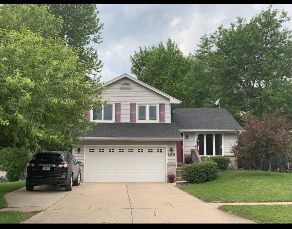 New dark shingle roof on a two-story home with attached garage by Hutch Unlimited Roofing, Iowa