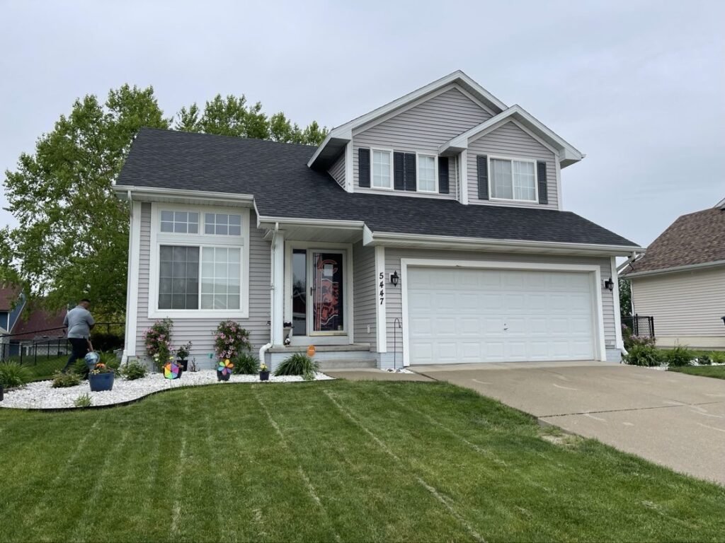 New dark shingle roof with white trim on a two-story home by Hutch Unlimited Roofing, Iowa