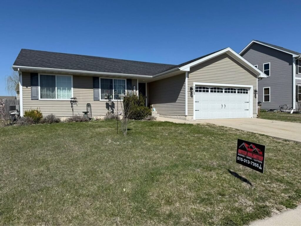 Completed shingle roof on a ranch home with Hutch Unlimited Roofing yard sign, Iowa