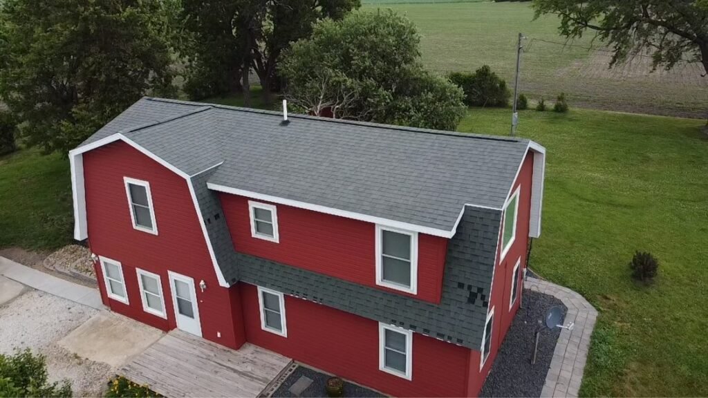 Aerial view of new gray shingle roof on a red gambrel-style home by Hutch Unlimited Roofing, Iowa