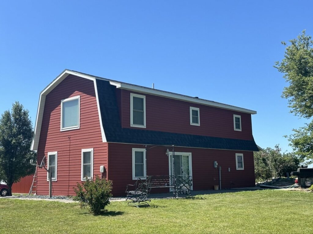 Finished gray shingle roof on a red gambrel-style home by Hutch Unlimited Roofing, Iowa