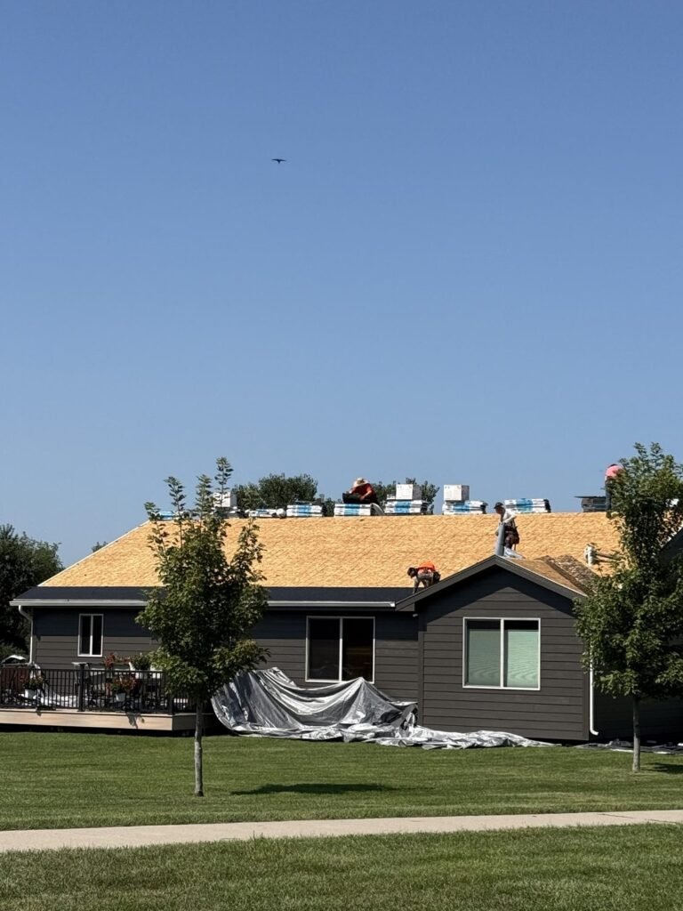Roof tear-off in progress with new decking and shingle bundles staged by Hutch Unlimited Roofing in Grimes, Iowa