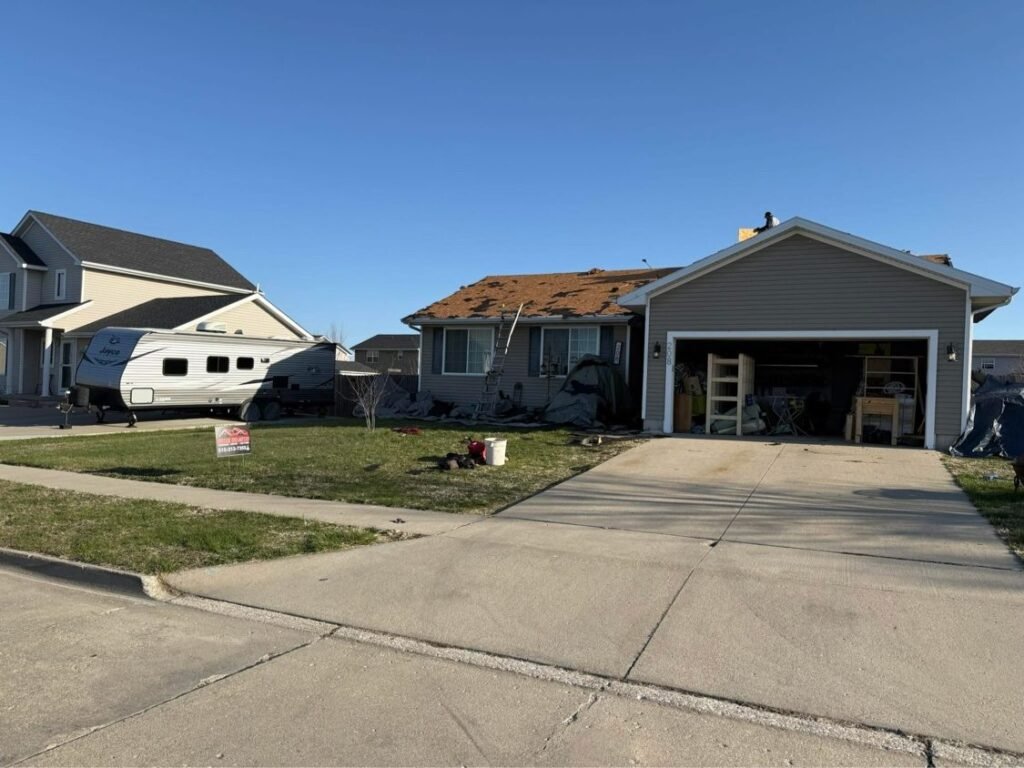 Roof tear-off in progress with crew on the roof by Hutch Unlimited Roofing, Iowa