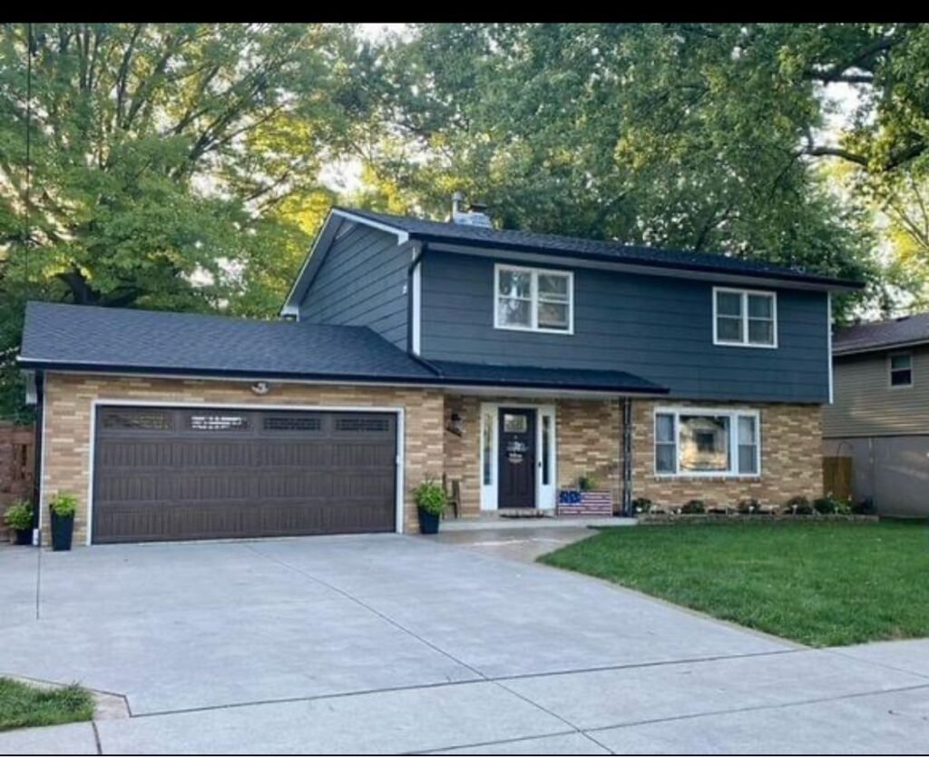 New dark shingle roof on a split-level home with brick garage by Hutch Unlimited Roofing, Iowa