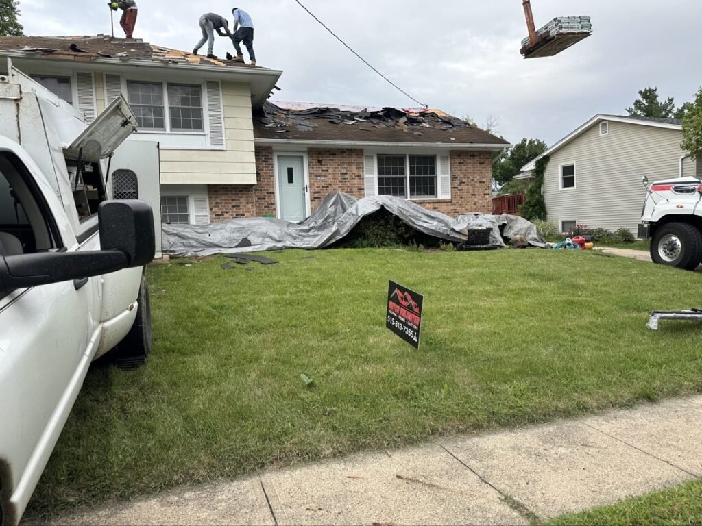 Hutch Unlimited Roofing crew tearing off a split-level home roof with new shingles being lifted by crane, Iowa